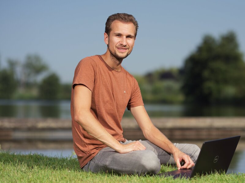 Dennis Sebregts zittend voor een laptop op het grasveld